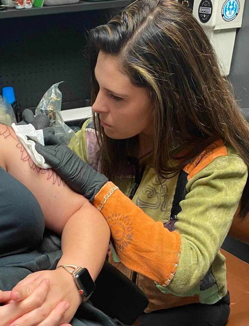 Rachel tattooing a client’s upper arm at Till Death Tattoo Studio